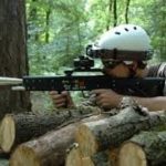 jeune homme jouant au laser game extérieur